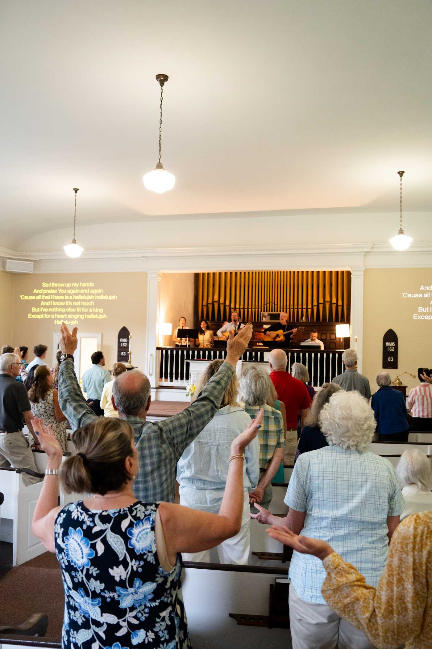 Congregation worshipping with hands raised at The Etna Church